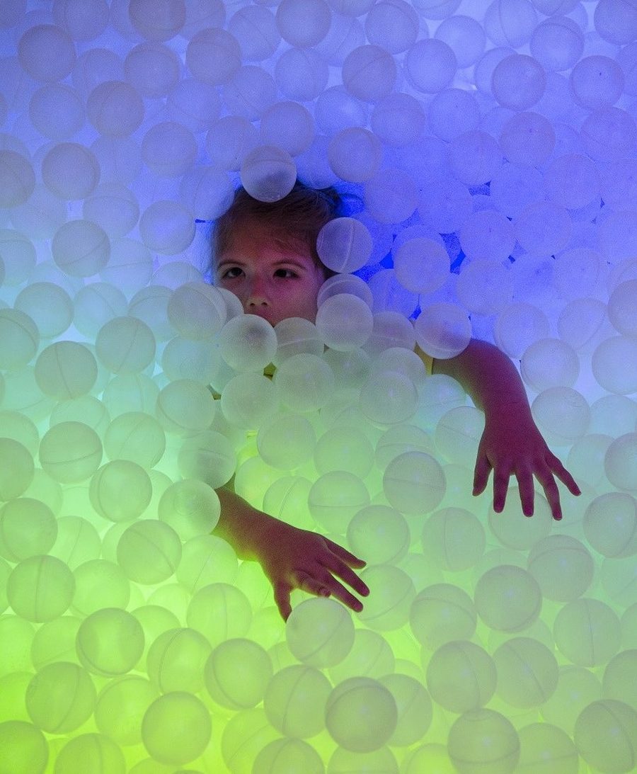 A child playing in a glowing sensory ball pit.